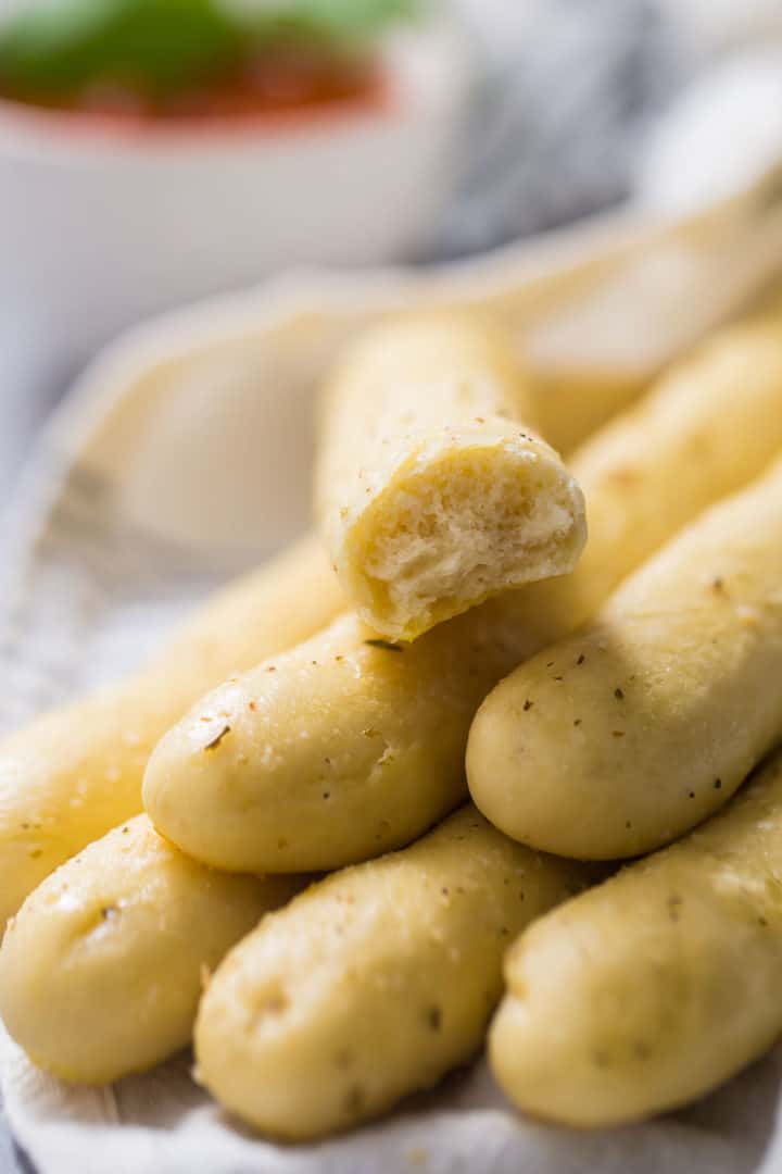 Close up image of a bundle of soft Italian breadsticks bathed in garlic butter and herbs.