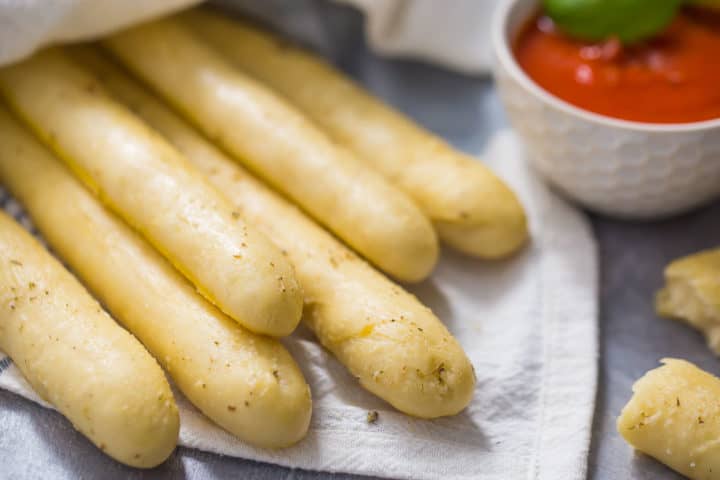 Horizontal image of a bundle of freshly baked soft garlic breadsticks. 