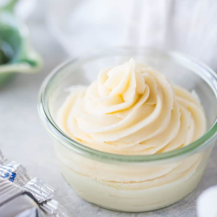 Small glass bowl containing cream cheese frosting piped in a swirl with a star tip.