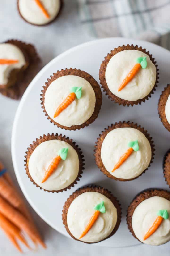 Overhead view of carrot cake cupcakes topped with cream cheese frosting piped to look like a carrot.