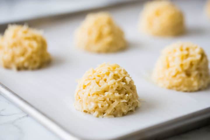 Unbaked coconut macaroons scooped onto a parchment-lined baking sheet.