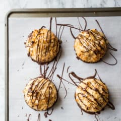 Overhead close-up shot of coconut macaroons drizzled with dark chocolate.