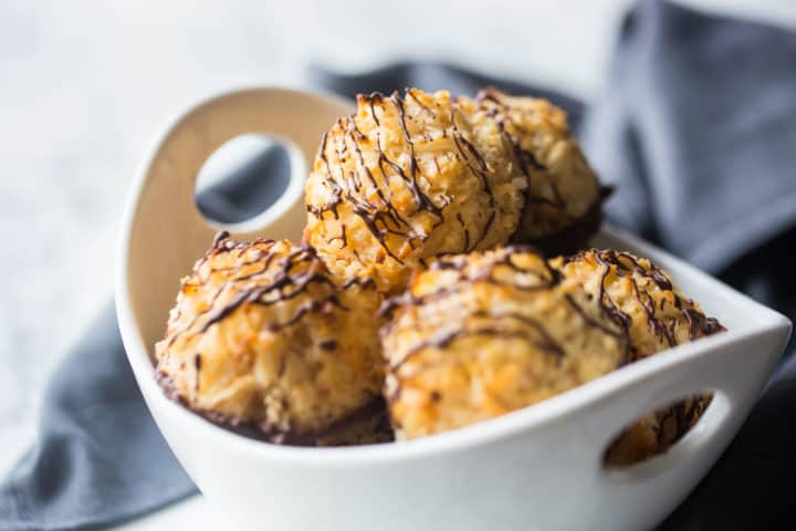 Bowl full of coconut macaroons with dark chocolate drizzle.