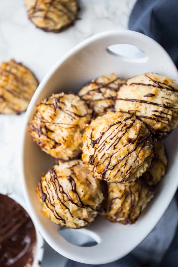 Overhead image of chocolate dipped coconut macaroons in a white bowl.