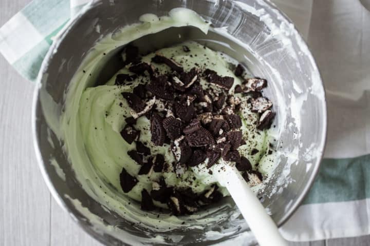 Grasshopper pie filling with crushed oreos in a stainless mixing bowl.