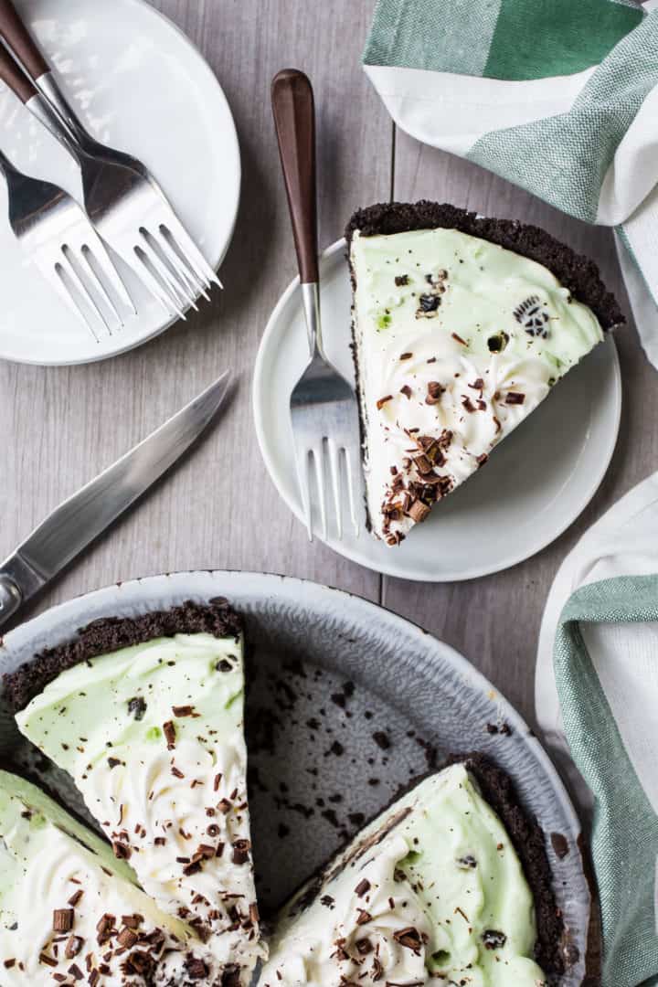 Overhead image of grasshopper pie sliced on plates with brown handled forks.