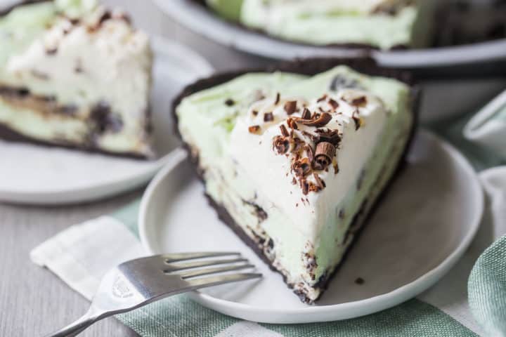 Slice of grasshopper pie on a white plate with a fork.