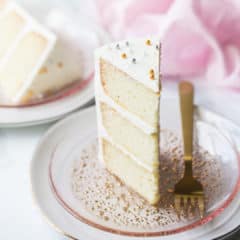Triple layer slice of white almond sour cream cake on a pink plate.