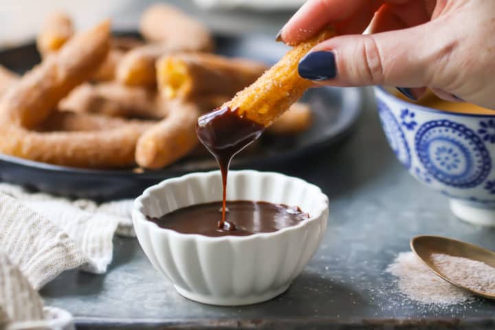 Dipping churros into chocolate sauce.