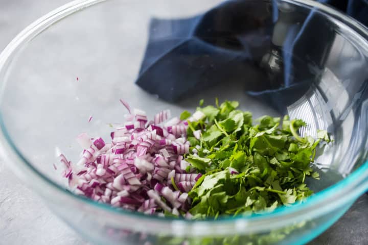 Red onion and cilantro in a large glass bowl.