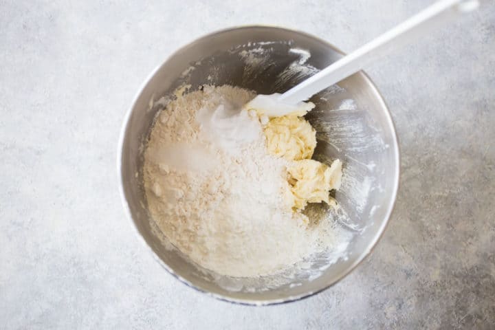 Adding dry ingredients to dough for sugar cookie bars.