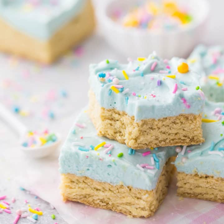 Stack of sugar cookie bars with pale aqua frosting and sprinkles.