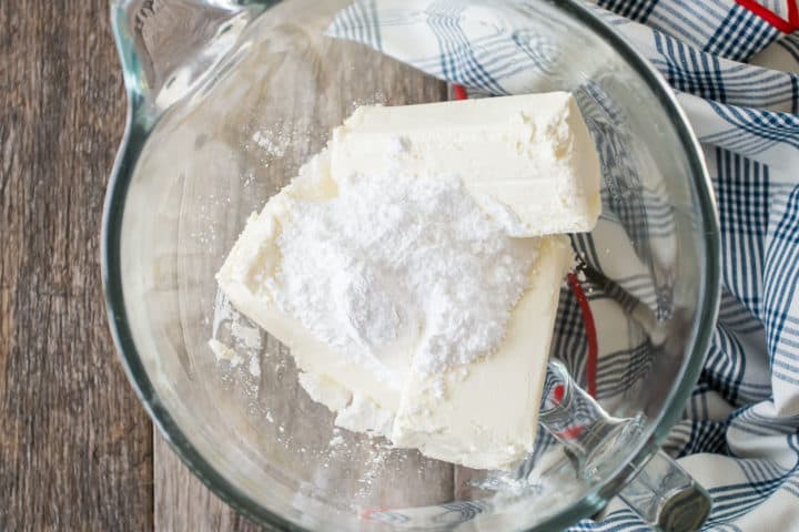 Cream cheese and powdered sugar in a large glass mixing bowl.