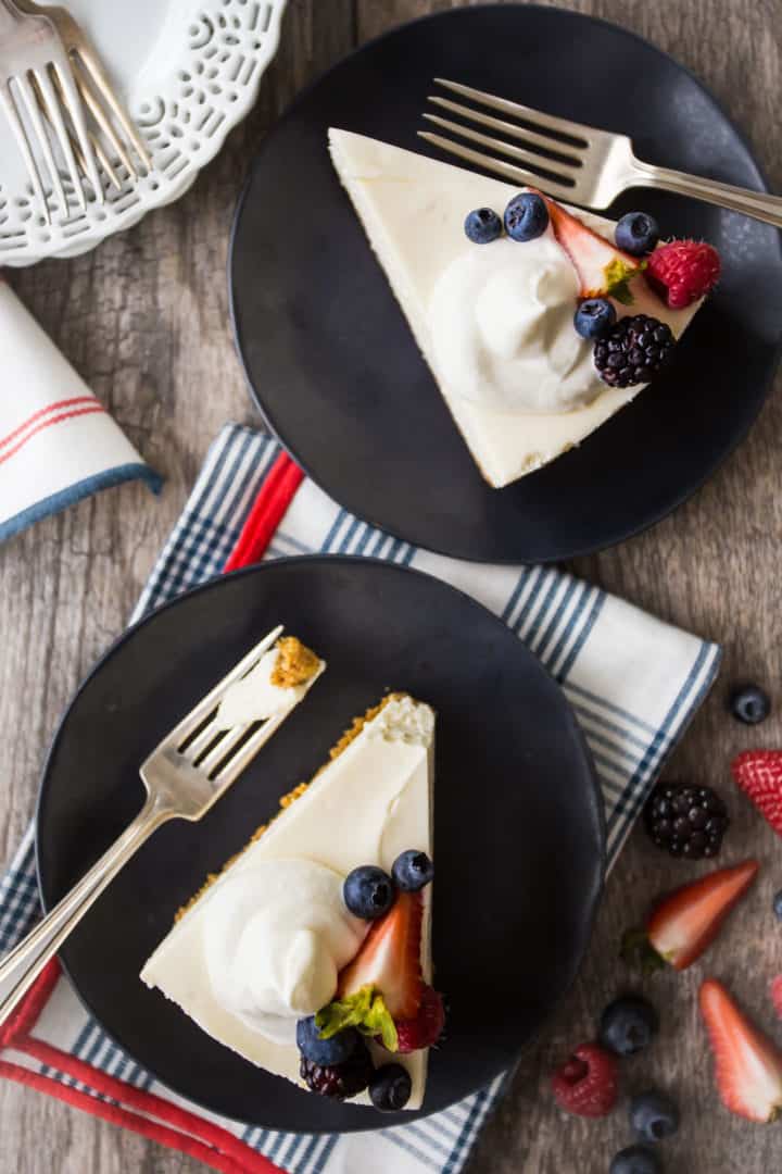 Overhead image of two slices of no-bake cheesecake with whipped cream and berries.
