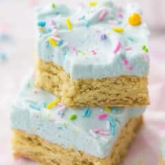 Pastel colored frosted sugar cookie bars with sprinkles and a pink napkin.