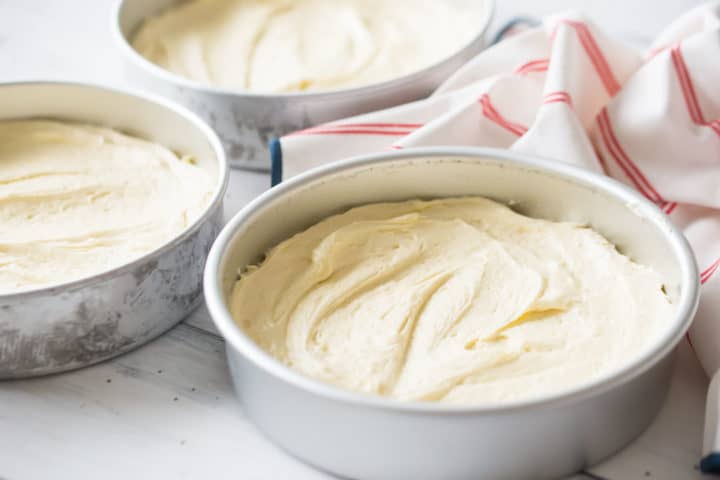 Unbaked pound cake layers in round aluminum baking pans.