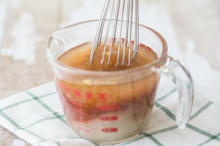 Whisking asian salad dressing in a measuring cup.