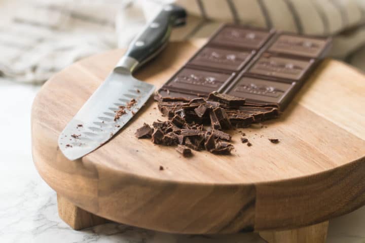 Chopping chocolate on a wooden cutting board.