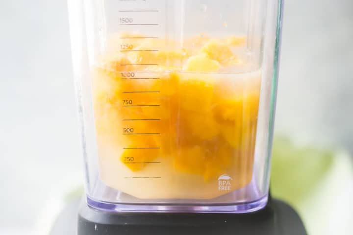 Making mango margaritas in a blender.