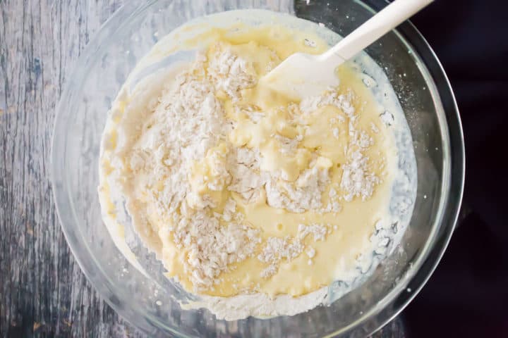 Lemon muffin batter being stirred together in a large mixing bowl.