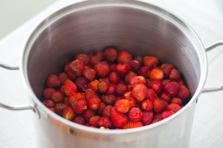 Large pot filled with hulled strawberries.