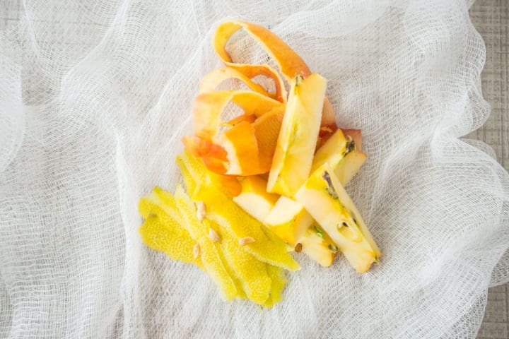 Lemon and apple peels, apple cores, and lemon seeds on cheesecloth.