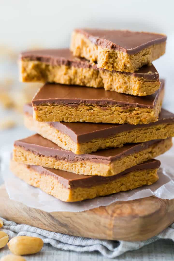 Tall stack of peanut butter chocolate bars with the top one broken in half.