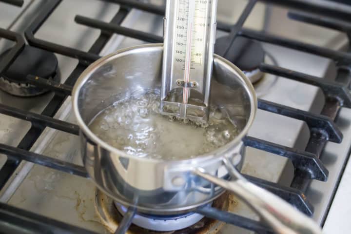 Boiling sugar syrup in a small pot with a candy thermometer.