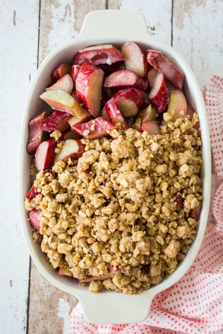Covering rhubarb crisp filling with crumb topping.