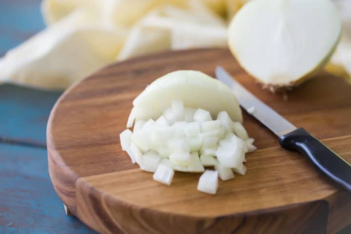 Chopped onion on a wooden cutting board.