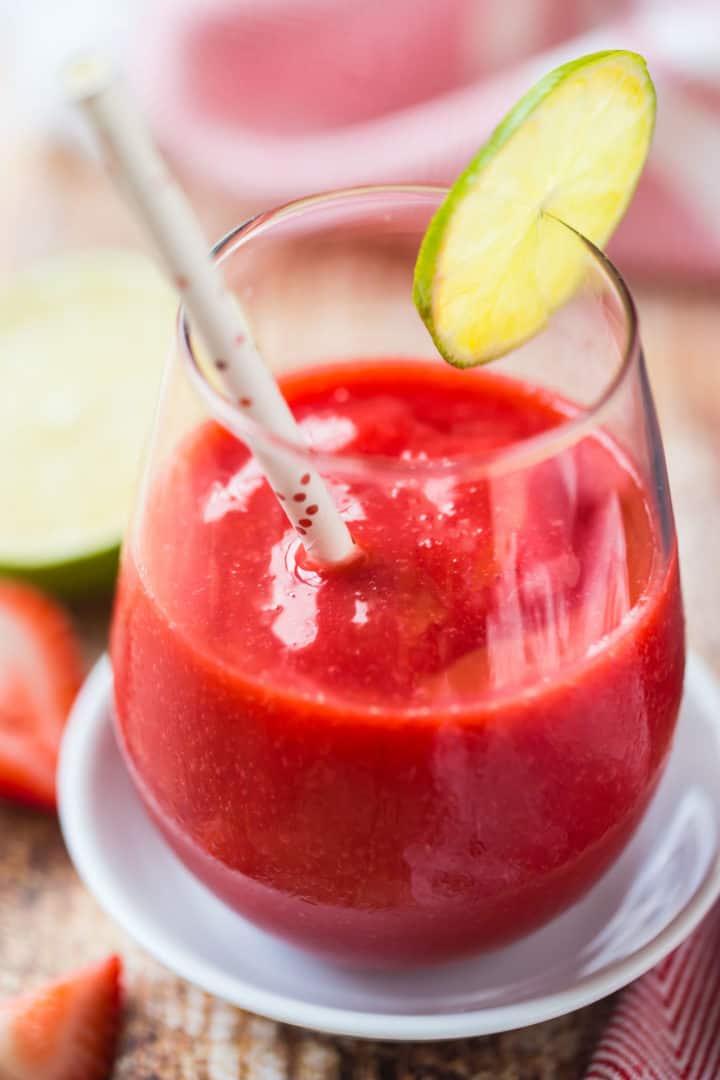 Close up of a frozen strawberry daiquiri slush, garnished with a slice of lime.