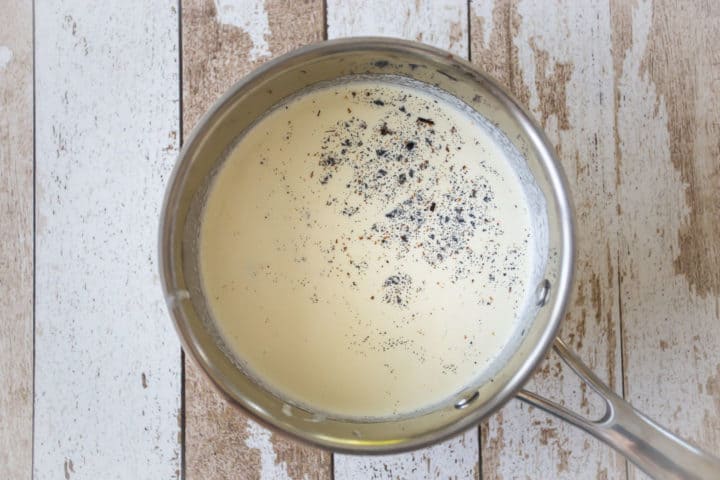 Heavy cream in a small pot with vanilla bean seeds added.