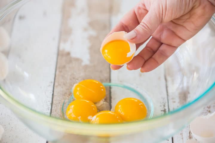 Separating eggs and placing the yolks in a large glass bowl.
