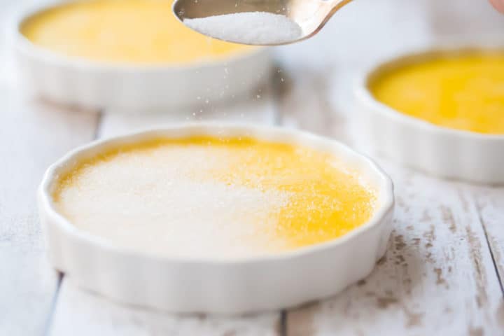 Topping creme brulee with granulated sugar.