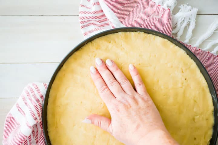Pressing sugar cookie dough into a pizza pan.