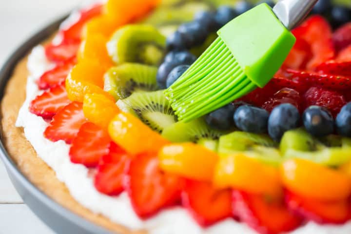 Brushing shiny glaze over fruit with a silicone pastry brush.