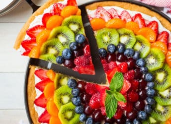 Removing a slice from a rainbow fruit pizza.