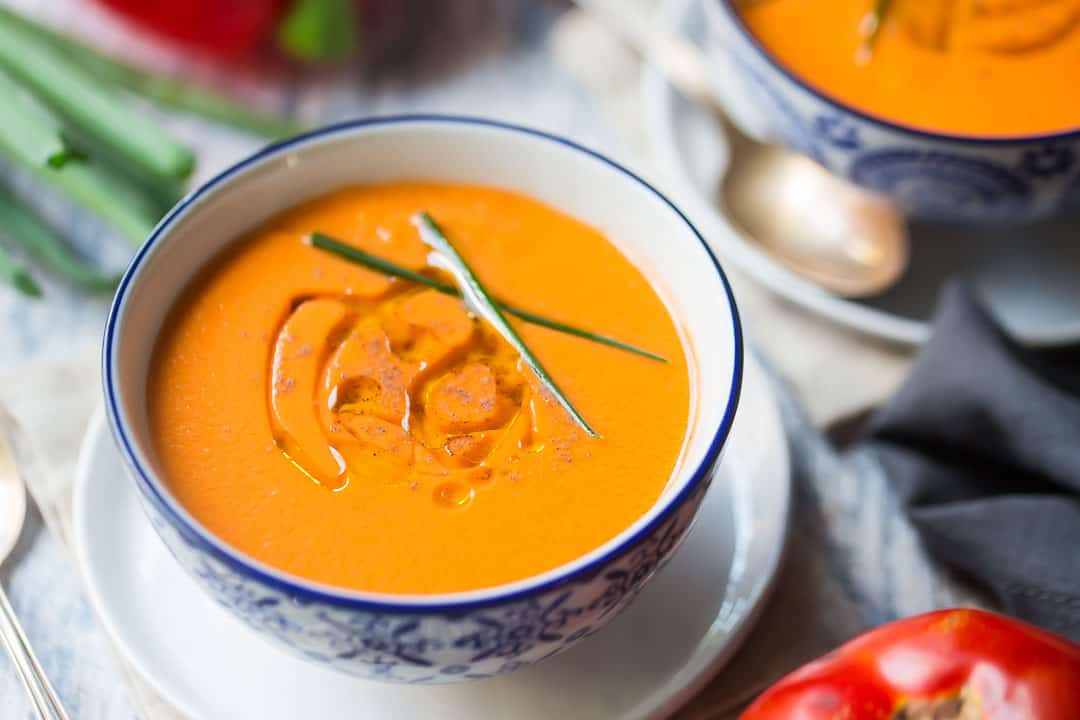 Horizontal image of traditional gazpacho soup, drizzled with olive oil and garnished with fresh chives.