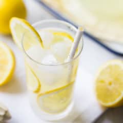 Tall glass of lemonade with ice and slices of fresh lemon.
