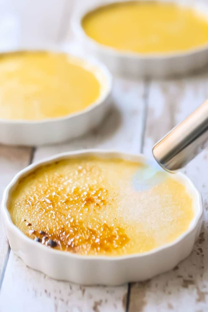 Bruleeing sugar topping on creme brulee with a kitchen torch.