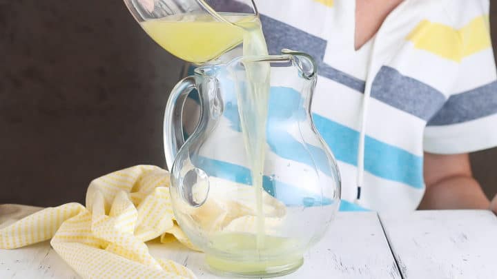 Pouring lemon juice into a glass pitcher.