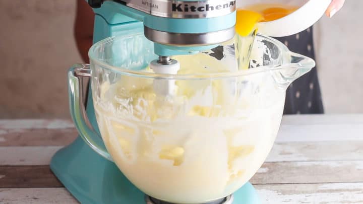 Adding eggs to cheesecake batter one at a time.