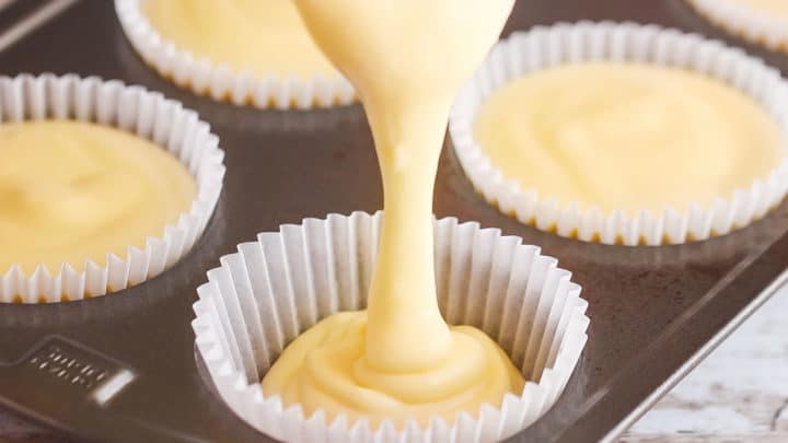 Pouring cheesecake batter into a cupcake pan.
