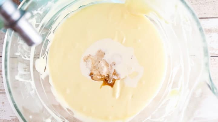 Adding egg yolk, cream, and vanilla to cheesecake batter.