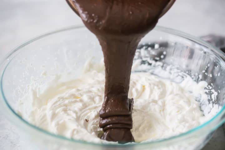 Pouring chocolate into whipped cream.