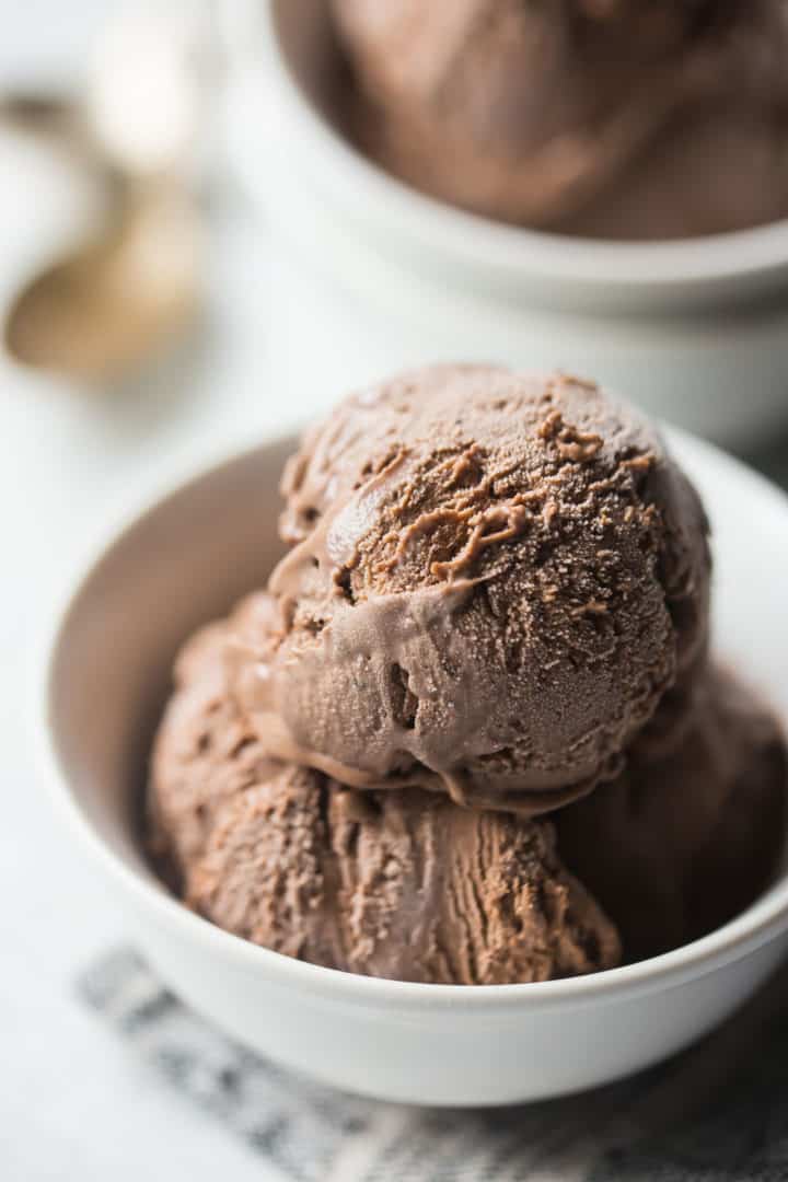 Homemade chocolate ice cream in a white bowl on a gray napkin.