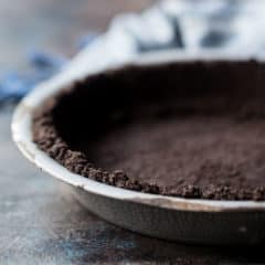 Close-up image of a homemade oreo cookie crust in a vintage pie dish.