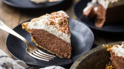 Slices of chocolate pie on dark plates with a wood background.