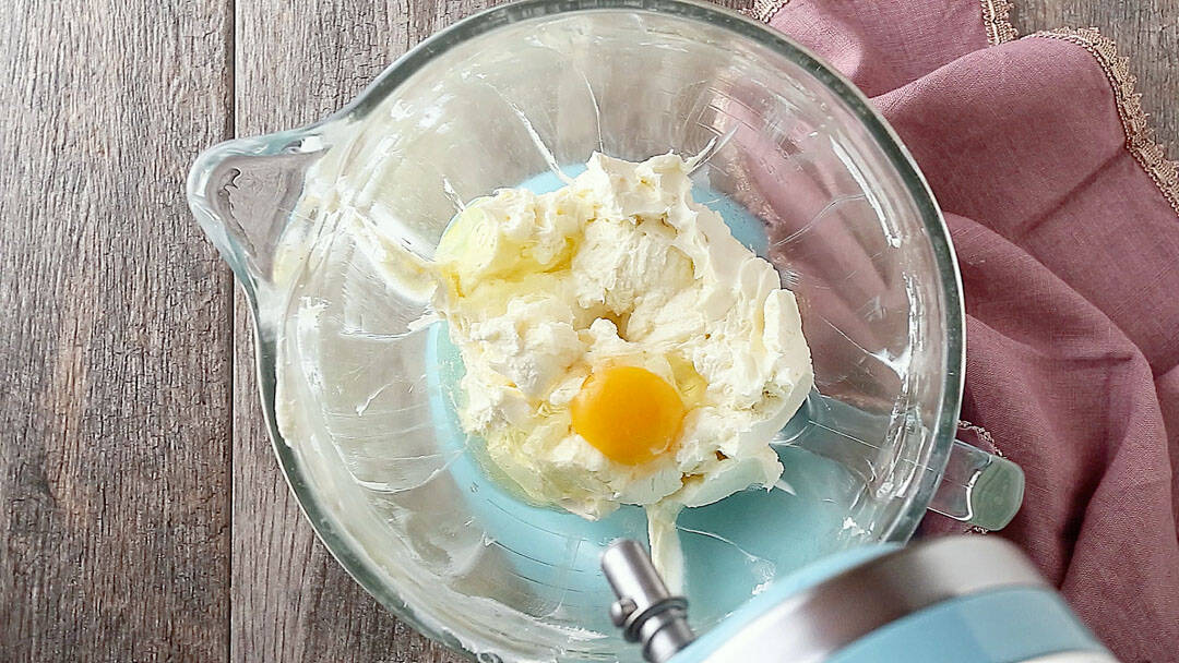 Adding eggs to cheesecake batter.