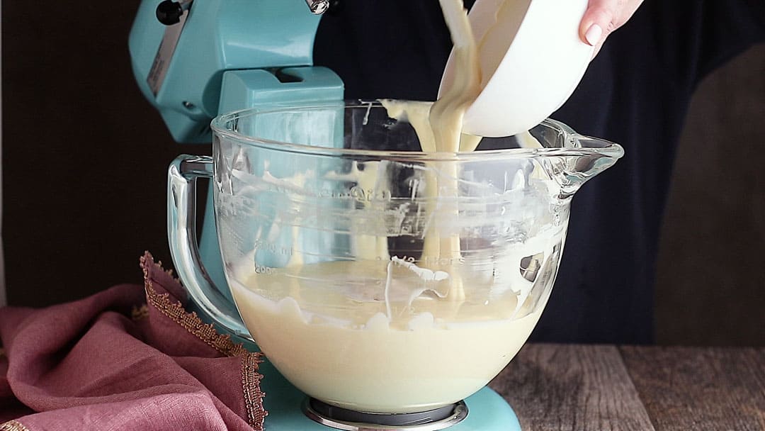 Adding melted white chocolate to cheesecake batter.